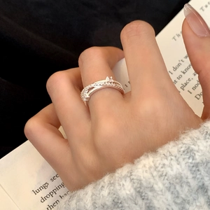 Elegant silver-colored crossed ring with micro-set zircons on dark background