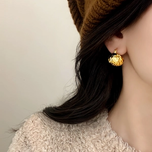 Vintage golden spherical earrings with geometric texture shown on a female model