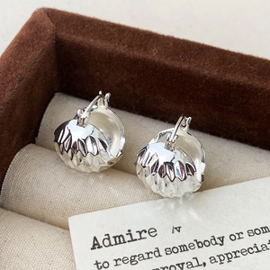 Macro view of silver hoop earrings with textured semi-spheres in a brown velvet box