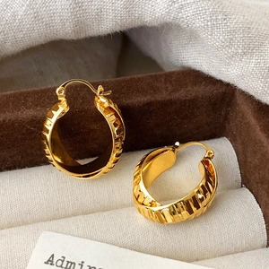 Elegant gold-tone ribbed hoop earrings displayed in a luxury jewelry gift box