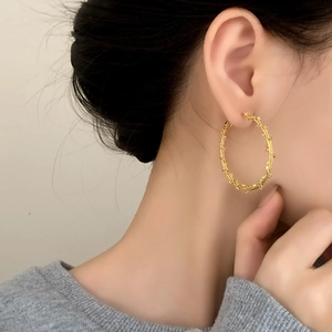 Golden geometric hoop earrings featuring intricate star charms on a minimalist female model