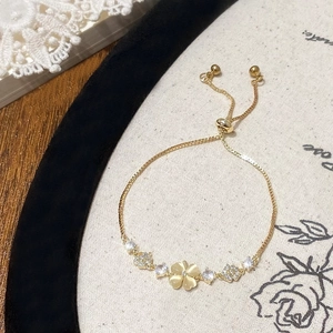 Detail of adjustable gold bracelet with cat eye stone clover and sparkling rhinestones