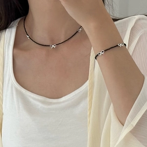 Elegant beaded necklace and bracelet set with silver bow charms on a black bead chain