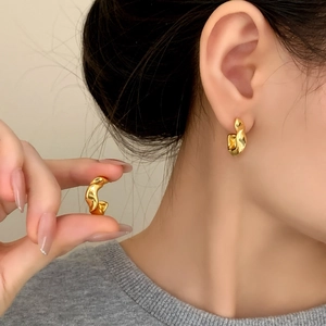 Elegant gold irregular twisted hoop earrings with a liquid metal texture on female model