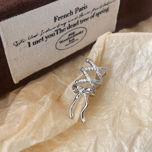 Detailed view of silver bow ear cuff with pavé crystals on a vintage velvet jewelry box