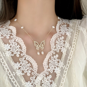 Elegant French style gold butterfly necklace with freshwater pearls on white lace model