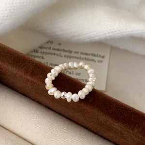 Minimalist French style freshwater pearl ring with a silver bead on velvet background