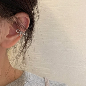 Orecchino ear cuff a fiocco argento minimalista mostrato in primo piano su una modella