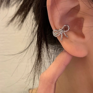 Orecchino a clip a fiocco in argento minimalista, mostrato sull'orecchio in primo piano