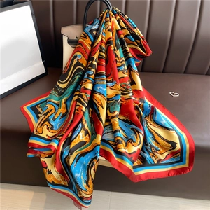 Elegant large silk scarf with red abstract swirl pattern draped on a stylish beige handbag