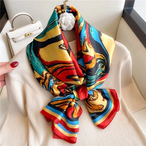 Detail of satin scarf with red and blue paisley patterns and camellia accessory