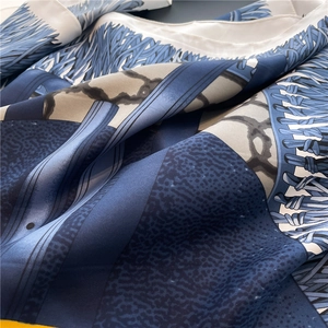 Detailed close-up showing the smooth satin texture and blue geometric prints of the silk scarf