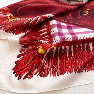 Detailed macro view of red horse harness and tassel print on a luxury silk scarf