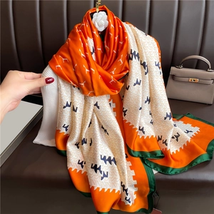 Luxurious long silk scarf with orange and green geometric patterns on a mannequin