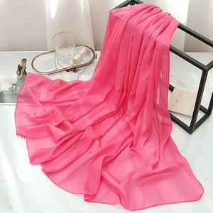 Detailed texture of rose pink chiffon scarf draped over a modern geometric metal stand