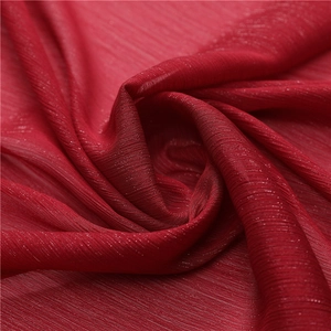 Macro detail of dark red pleated chiffon fabric with subtle shimmering metallic threads