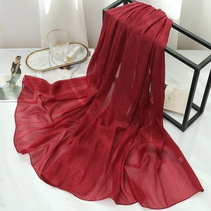 Macro detail of wine red chiffon scarf with shimmering silver silk and pleated texture