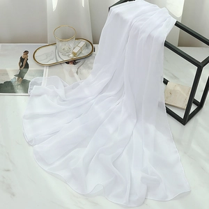 Detail of pure white chiffon scarf with subtle shimmer on a white marble background