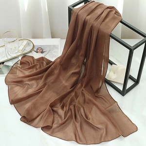 Close-up of brown chiffon scarf with metallic shimmer hanging on a minimalist frame