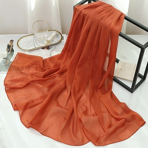 Close-up of orange pleated chiffon scarf with fine gold silk glitter and rolled hem edge