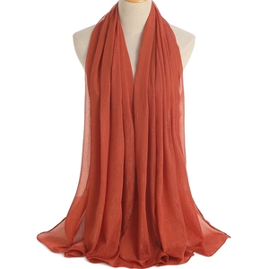 Close-up of brick red chiffon scarf with shimmering metallic threads and pleated texture