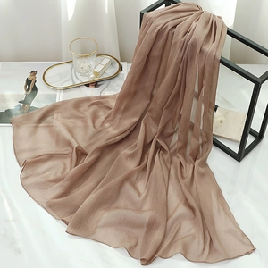 Detail of champagne gold chiffon scarf with shimmering metallic silk texture on marble