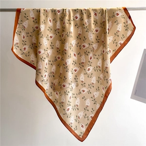 Elegant 70x70cm beige and orange paisley satin square scarf displayed on a metal stand