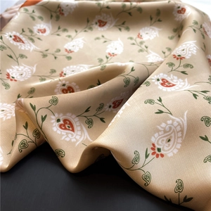 Detailed view of champagne silk scarf featuring floral paisley patterns and satin texture