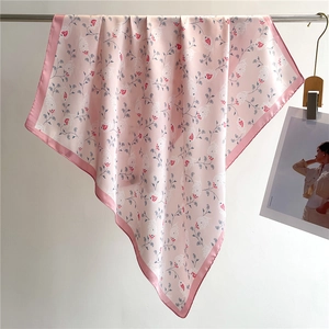 Detail of pink silk-like scarf with floral patterns and deep pink border on white background
