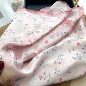 Detailed view of pink silk scarf with paisley pattern folded in a black gift box