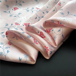 Close-up of pink satin scarf featuring paisley patterns and elegant floral print details