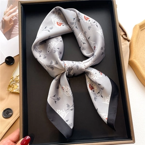 Detail of silver silk square scarf with paisley pattern folded in a gift box