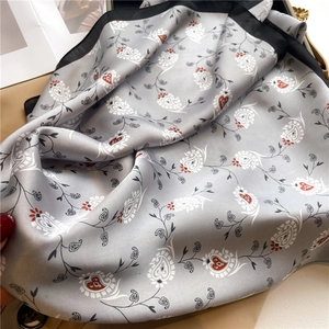 Detail of silver paisley silk scarf with black border showing satin texture and draping