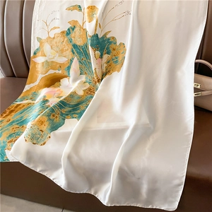 Détail d'une écharpe en soie avec imprimé lotus sur canapé montrant la texture du tissu