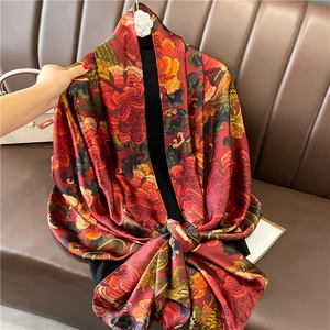 Écharpe de luxe en soie à fleurs avec broche camélia posée sur un canapé en cuir