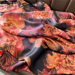 Détail d'un foulard en soie de luxe avec pivoines rouges et accents dorés satinés