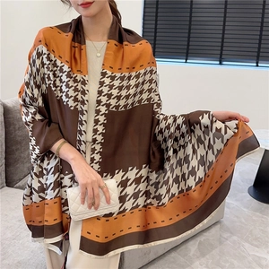 Détail d'une grande écharpe de luxe avec motif pied-de-poule marron et orange au fini soyeux