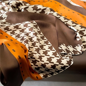 Détail d'un foulard en satin avec motifs géométriques et rayures orange soyeuses