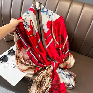 Détail d'un foulard en soie rouge avec motifs floraux vintage et châteaux sur cuir
