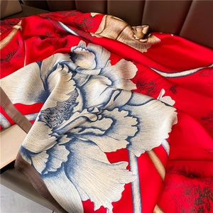 Détail de la texture d'un foulard en soie rouge avec imprimé pivoine et bords roulés