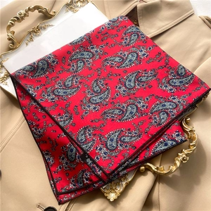 Detail of red paisley silk scarf with blue patterns on a vintage tray over a trench coat