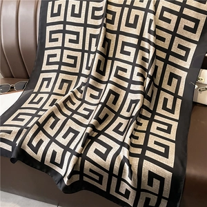 Détail d'une écharpe en soie douce à motifs géométriques sur un fond en cuir marron