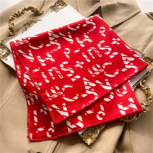 Detailed view of red geometric satin scarf with white typography on a trench coat