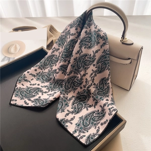 Close-up of pink paisley satin scarf with elegant texture on a leather bag