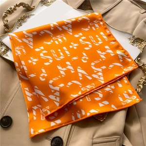 Close-up of orange satin neckerchief with white lettering on a beige trench coat