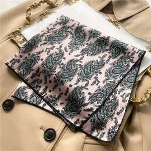Elegant paisley satin square scarf in beige displayed on a decorative gold tray