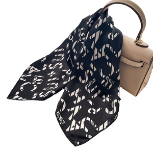 Minimalist black and white geometric letter silk scarf tied on a beige leather handbag