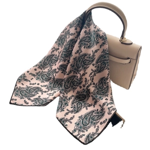 Pink satin neck scarf with green paisley print draped over a luxury handbag handle