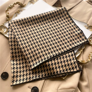 Detailed close-up of houndstooth silk scarf on a trench coat with elegant tray