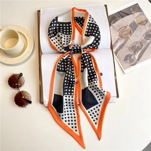 Detailed view of polka dot narrow silk scarf tied on a sketchbook with fashion accessories